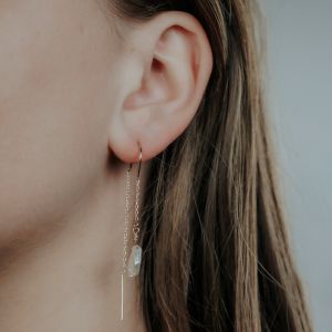 Durch die Ohrringperle ziehen